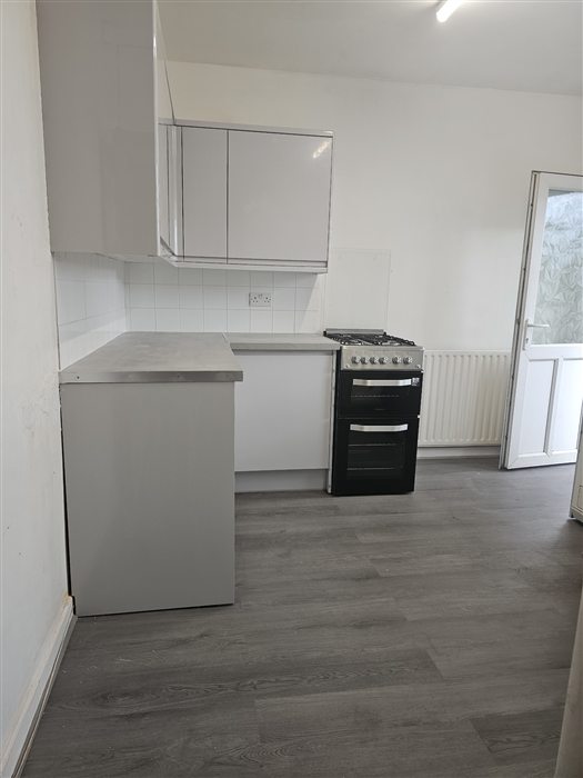 Same kitchen after: light gloss units and grey plank flooring