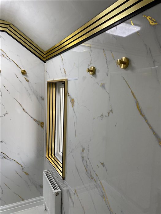 Shower room with marble-effect wall panels and brass window trim