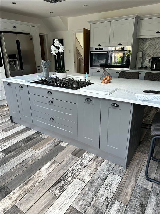 Grey shaker island with a gas hob and white worktop