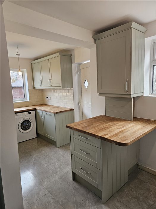 Sage shaker kitchen with an oak-topped peninsula