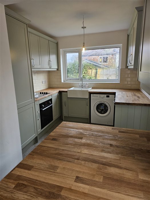 Sage green shaker kitchen with oak worktops and a butler sink