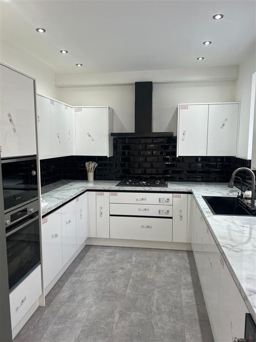 White gloss kitchen with black splashback and marble-effect worktop
