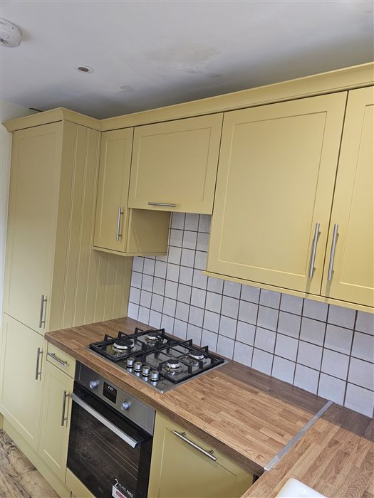 Pale yellow shaker kitchen with a gas hob