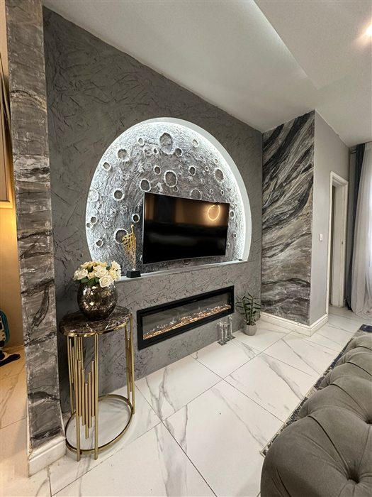 Media wall with an illuminated arch, stone-effect panels and a long electric fire