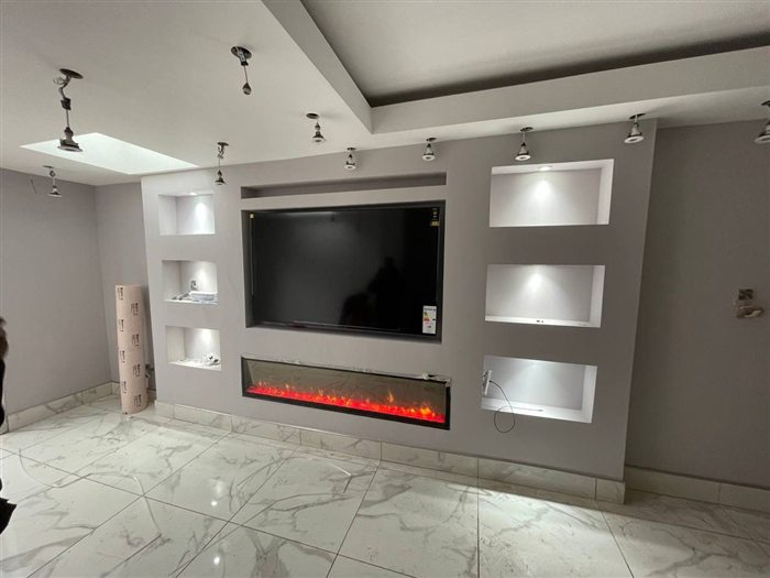 Grey media wall with lit shelving niches and an electric fire
