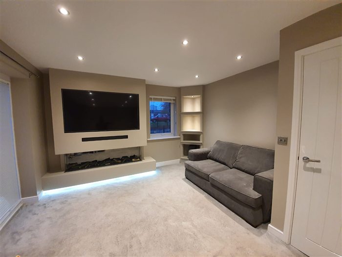 Lounge media wall with recessed TV and LED strip under a floating plinth