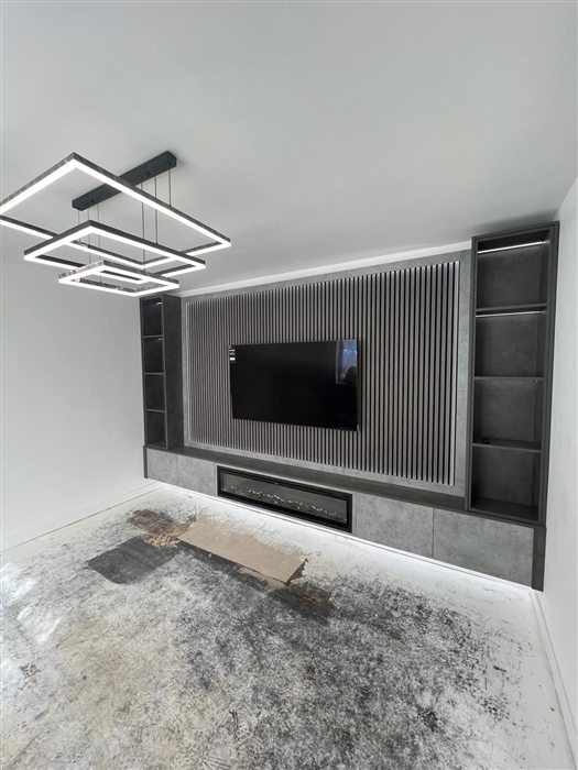 Grey slatted media wall with shelving and floating plinth