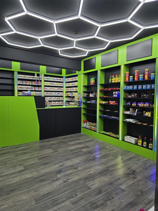 Shop fit-out with green shelving units and hexagon ceiling lights